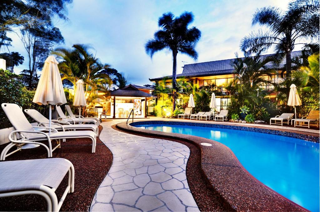 科夫斯港海滩走私者酒店的一座带椅子和遮阳伞的游泳池位于一座建筑旁边
