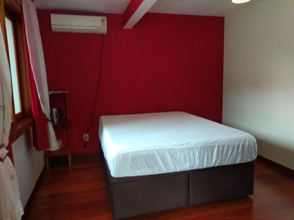 新彼得罗波利斯QUARTO Jardim da Serra的一间小卧室,在红色的墙上配有一张白色的床