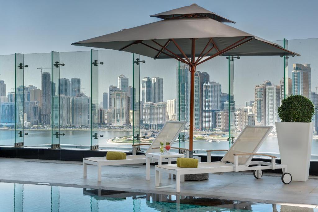 沙迦The Act Hotel Sharjah的庭院配有桌椅和遮阳伞。