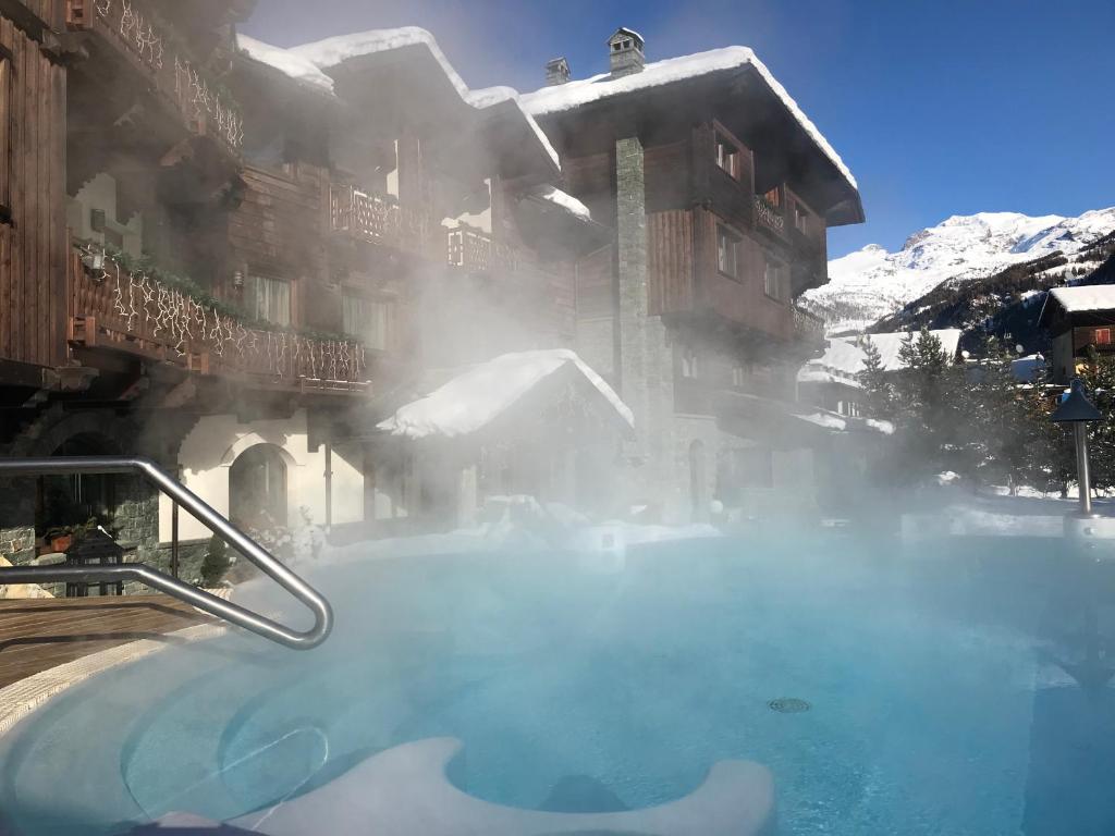 尚波吕克Hotel Relais Des Glaciers - Adults Only的一座积雪建筑前的热水浴池