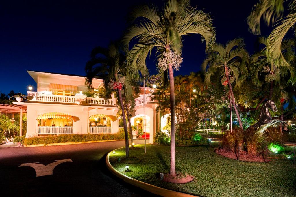 金斯敦特拉诺娃全套房酒店的一座白色的大建筑,前面有棕榈树
