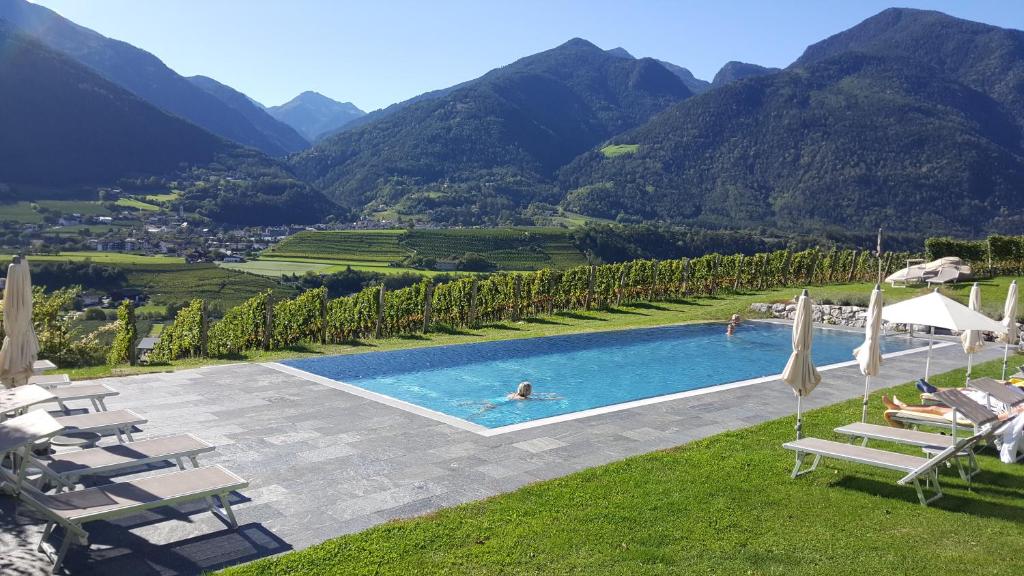 布列瑟农派诗豪肤酒店的一个带椅子的游泳池,背景是山脉