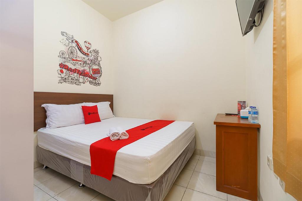 雅加达RedDoorz @ Tanjung Duren的一间卧室配有一张带红白毯子的床