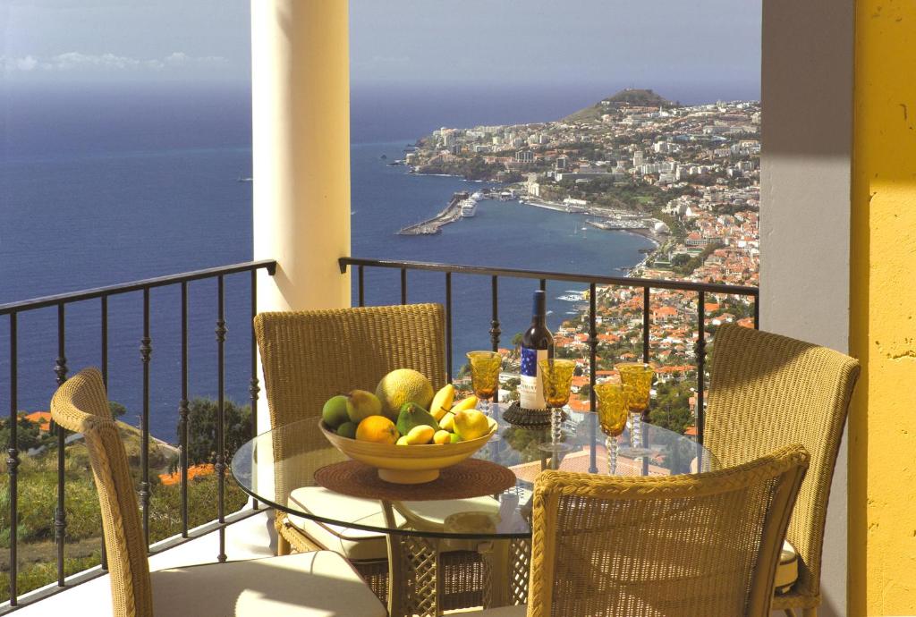 丰沙尔Luxury One Bedroom Palheiro Village by HR Madeira的阳台上的桌子上放着一碗水果