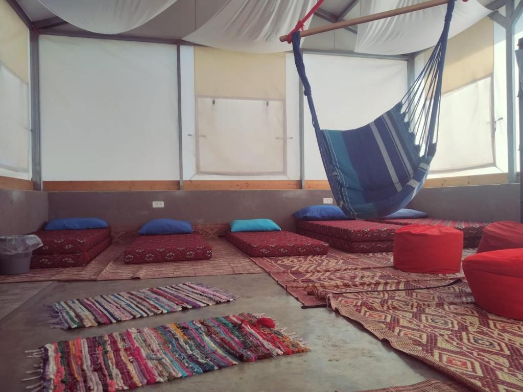Giv'at Yo'av西奈巴沟兰露营地的客房配有红色和蓝色的枕头以及吊床。