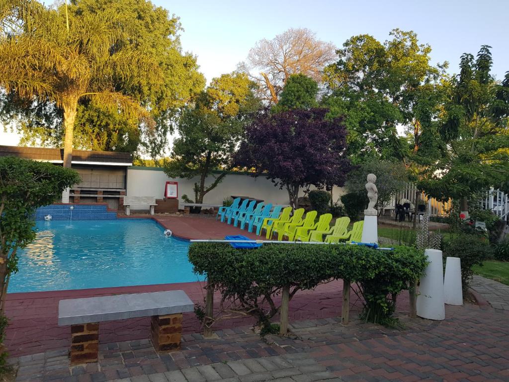 伯诺尼Good 2 Go Guest House的游泳池配有五颜六色的椅子和长凳