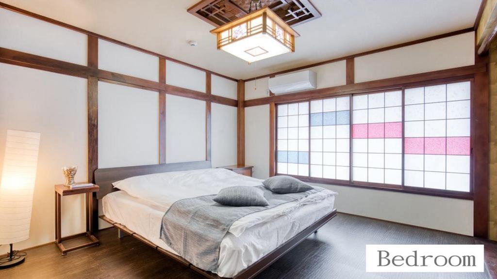大阪北巽サクラハウス一軒家 Sakura House Guest House Kitatatsumi 最大16名的卧室设有窗户和一张带两个枕头的床