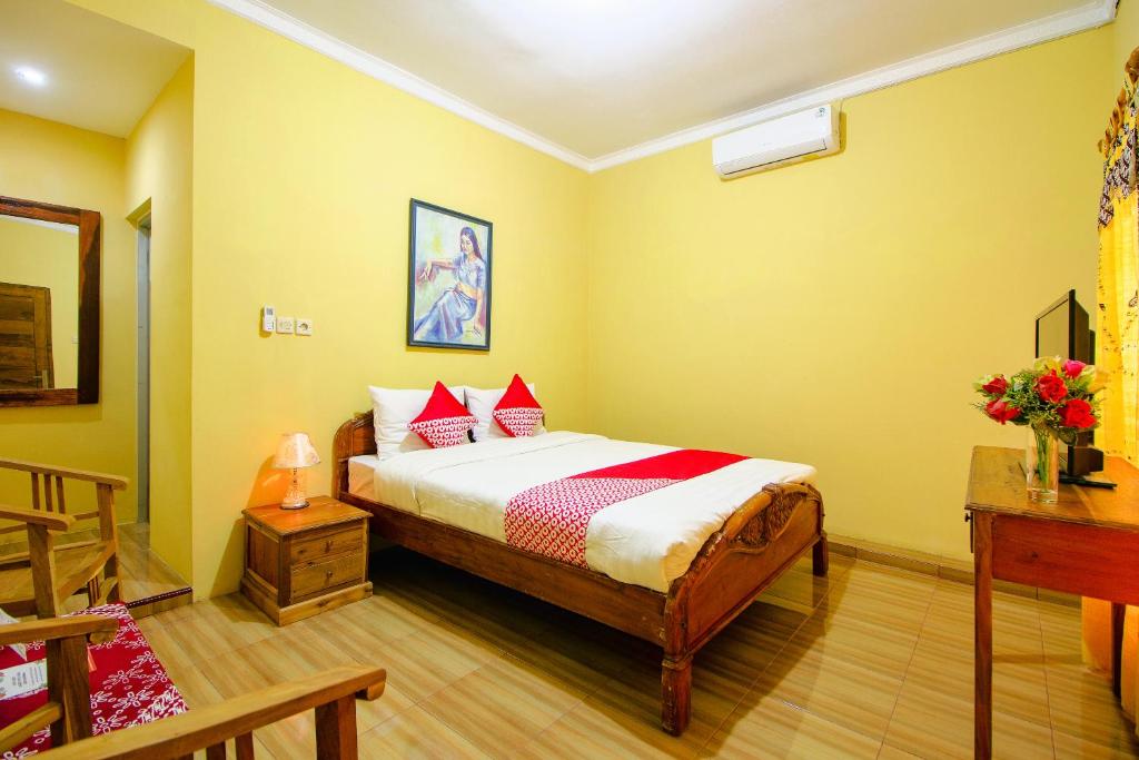 班图尔OYO 2047 Opak Village Bed & Breakfast的卧室配有一张床铺,位于一个黄色墙壁的房间