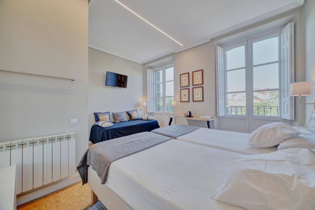 潘普洛纳Pensión Mendi的白色卧室设有一张大床和两个窗户