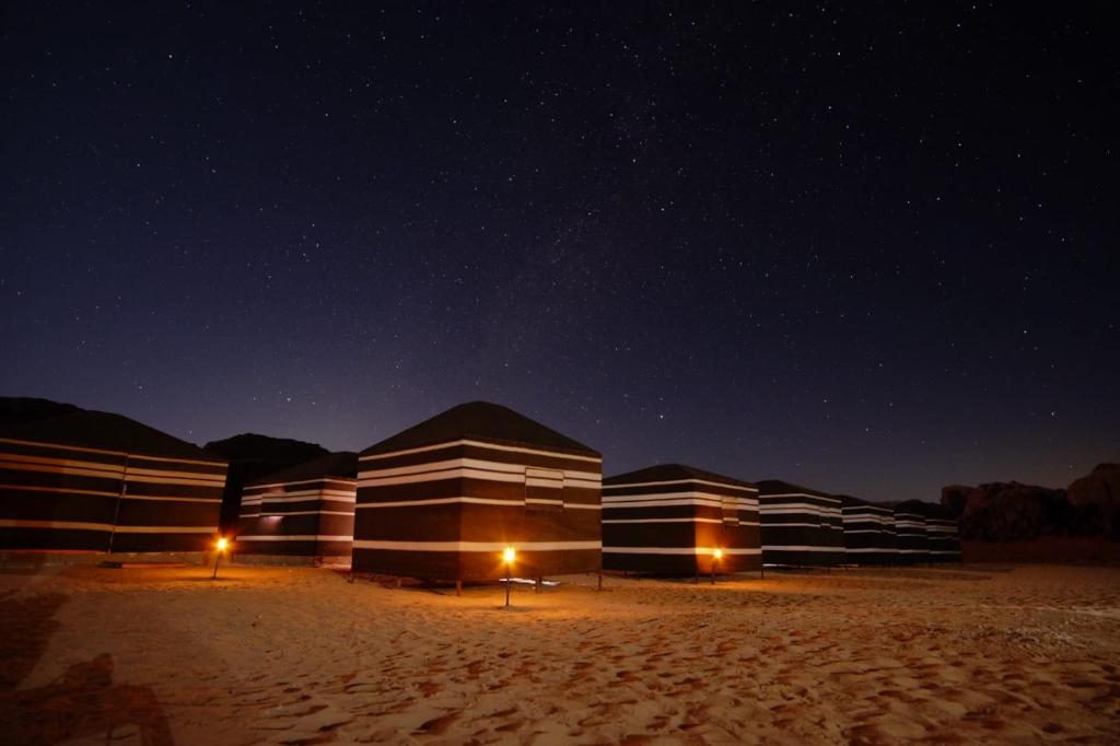 瓦迪拉姆Star City Camp wadirum的沙漠中一排夜空的建筑物