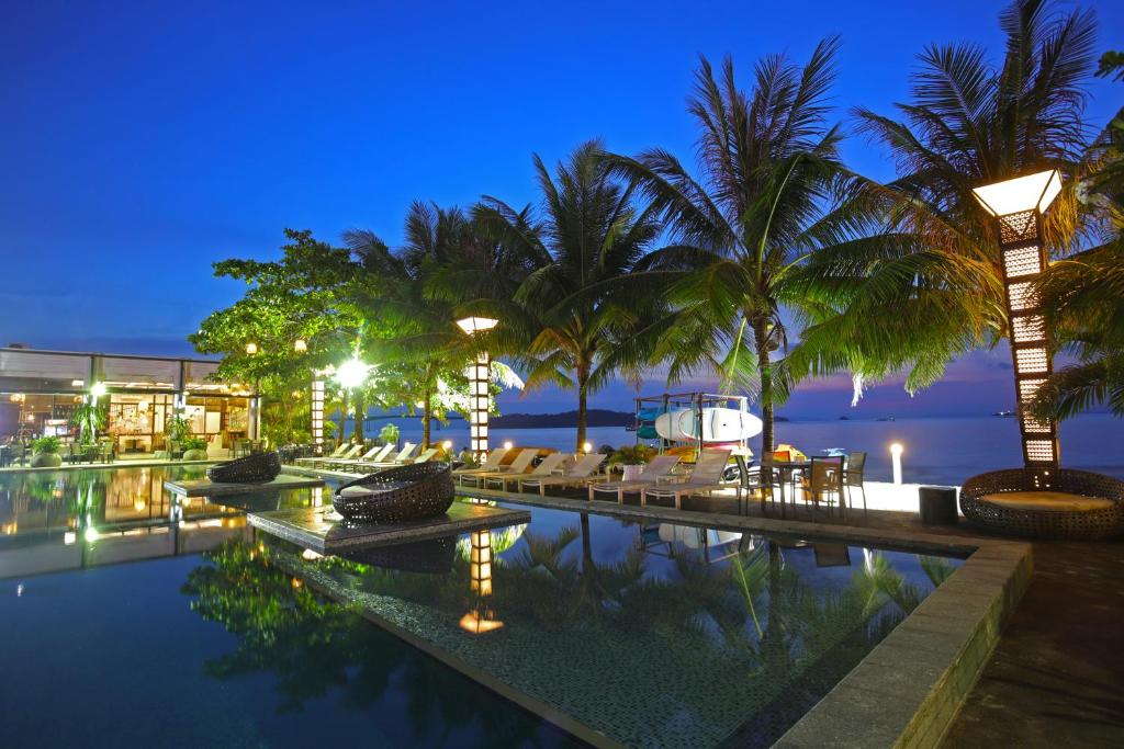 西哈努克坤科赌场酒店的度假村泳池,晚上有棕榈树和椅子