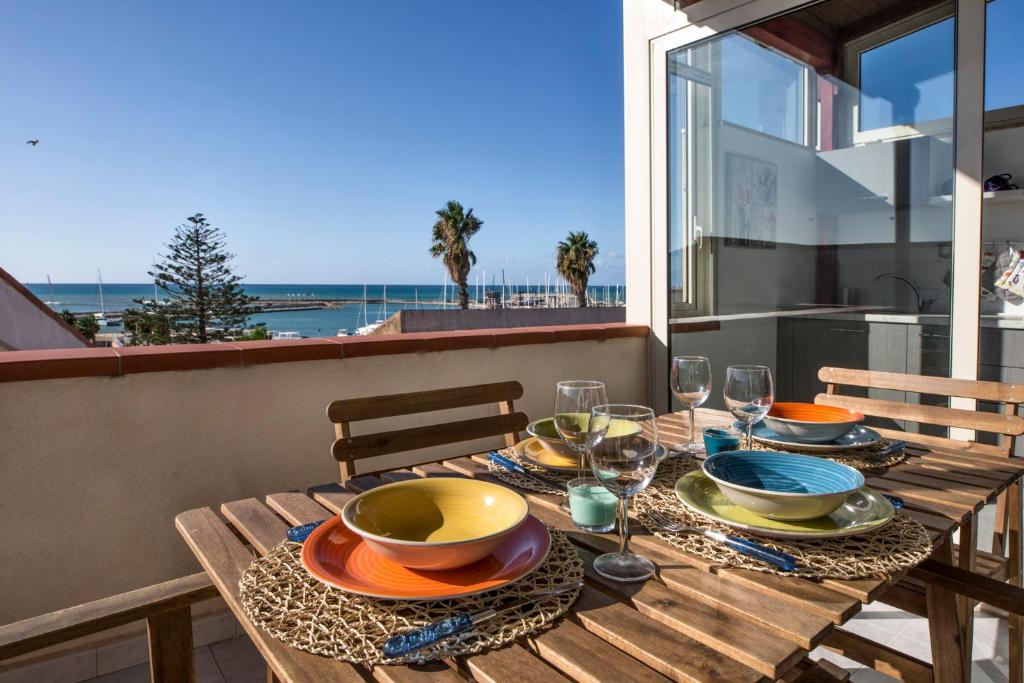 拉古萨码头siciliacasevacanze - Marina Domus 82的阳台上配有带盘子和酒杯的木桌