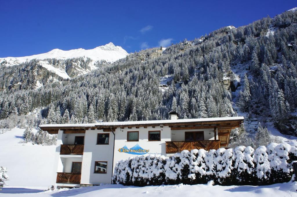 皮茨河谷圣莱昂哈德格莱赛小木屋酒店的一座被雪覆盖的建筑,背景是群山