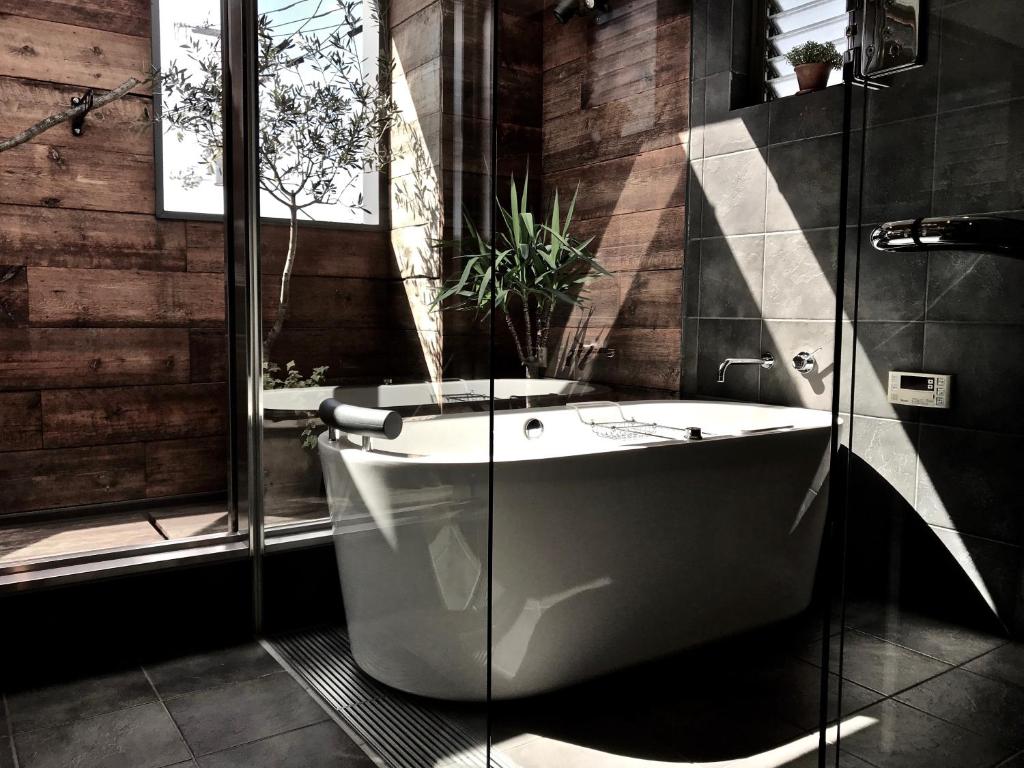高松maison de stuffmarket的带浴缸和玻璃淋浴间的浴室。