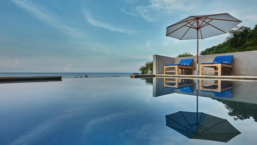 艾湄湾Villa Aska的一个带两把椅子和遮阳伞的游泳池