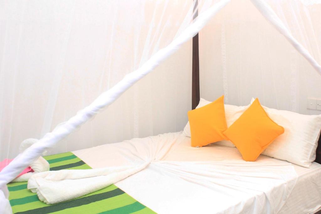锡吉里亚Hotel BEJEWELLED Sigiriya的一张带白色床单和黄色枕头的床