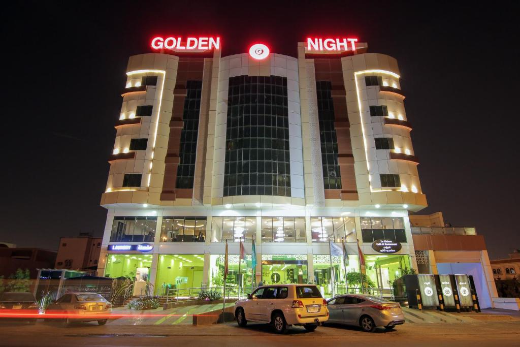 奈季兰Golden Night Hotel的前面有汽车停放的建筑