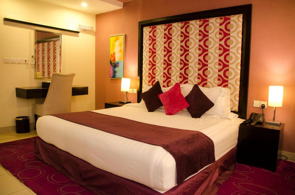 塔伊夫Swiss Spirit Hotel & Suites Taif的酒店客房配有一张带红色枕头的大床