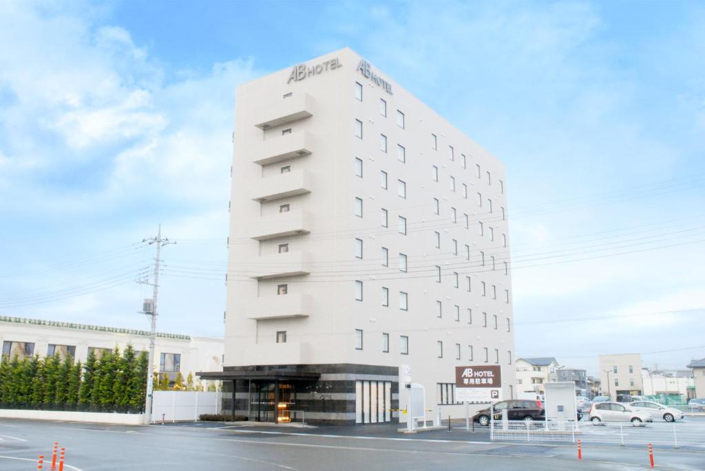 伊势崎市AB Hotel Isesaki的街道拐角处高大的白色建筑