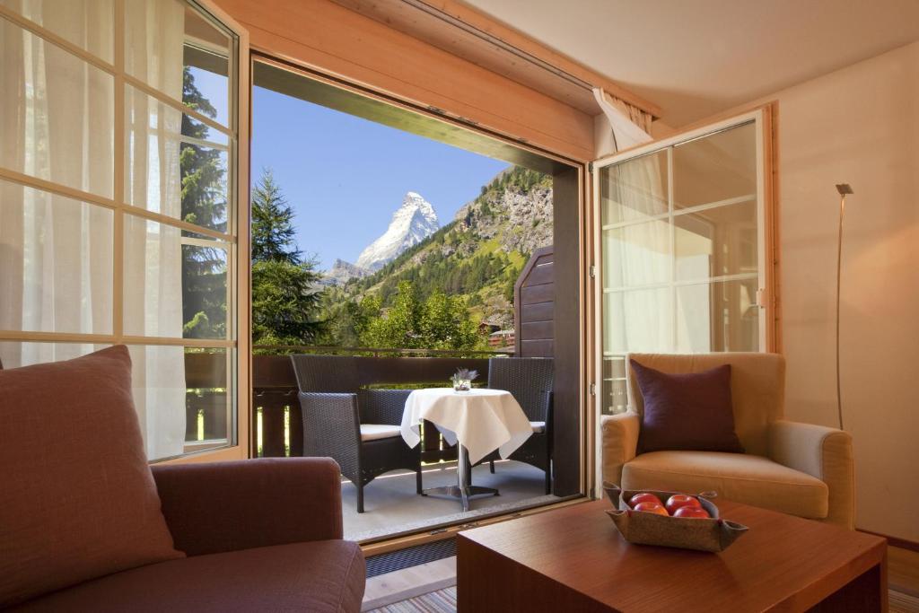 采尔马特Le Mirabeau Resort & Spa的客厅配有桌子,享有山景