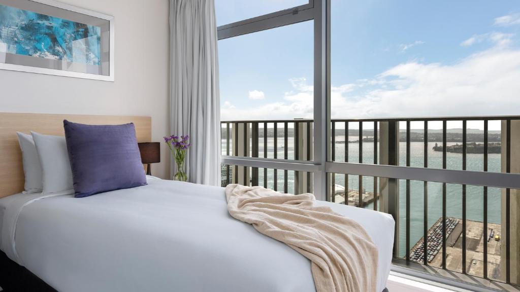 奥克兰Auckland Harbour Suites的一间卧室设有一张床和一个大窗户