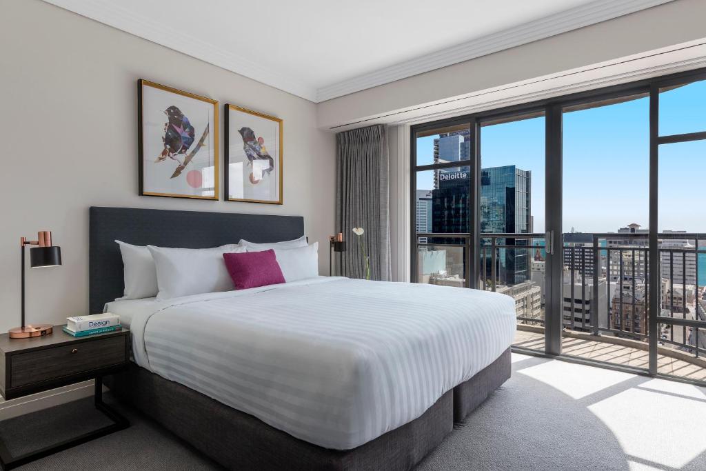 奥克兰Avani Metropolis Auckland Residences的一间卧室设有一张大床和一个大窗户