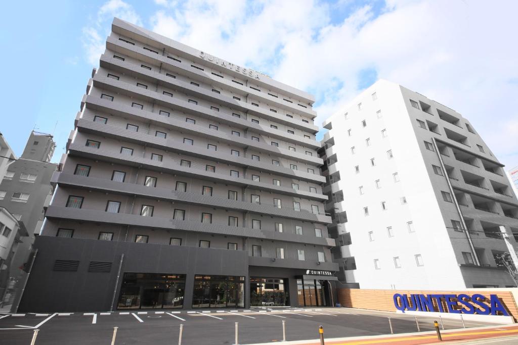 福冈Quintessa Hotel Fukuoka Tenjin Minami的停车场旁两座高大的白色建筑