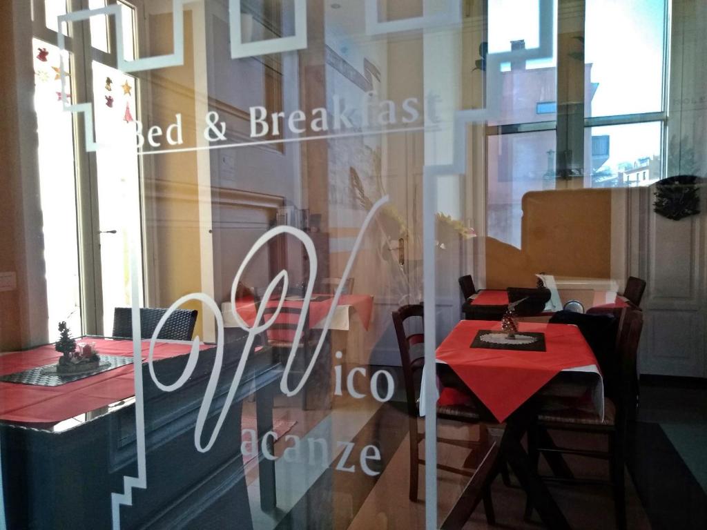 维科德尔加尔加诺B&B Vico Vacanze的餐厅在窗户上摆放着红色的桌子和椅子