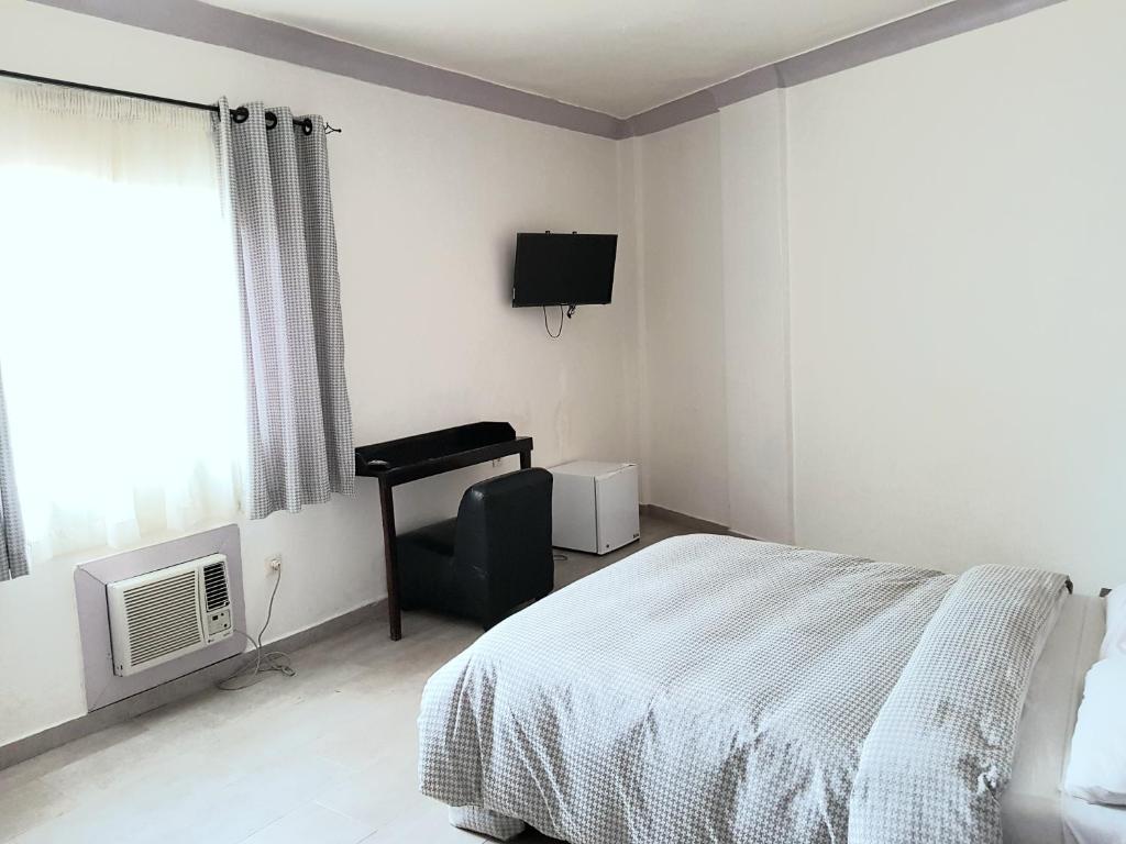 科纳克里Hotel du Golfe de Guinée的一间卧室配有一张床、一把椅子和电视