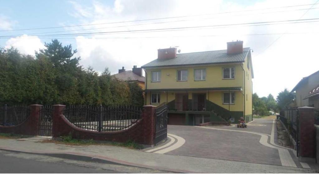 TrzebowniskoPokoje Jasionka Zaczernie的前面有栅栏的黄色房子