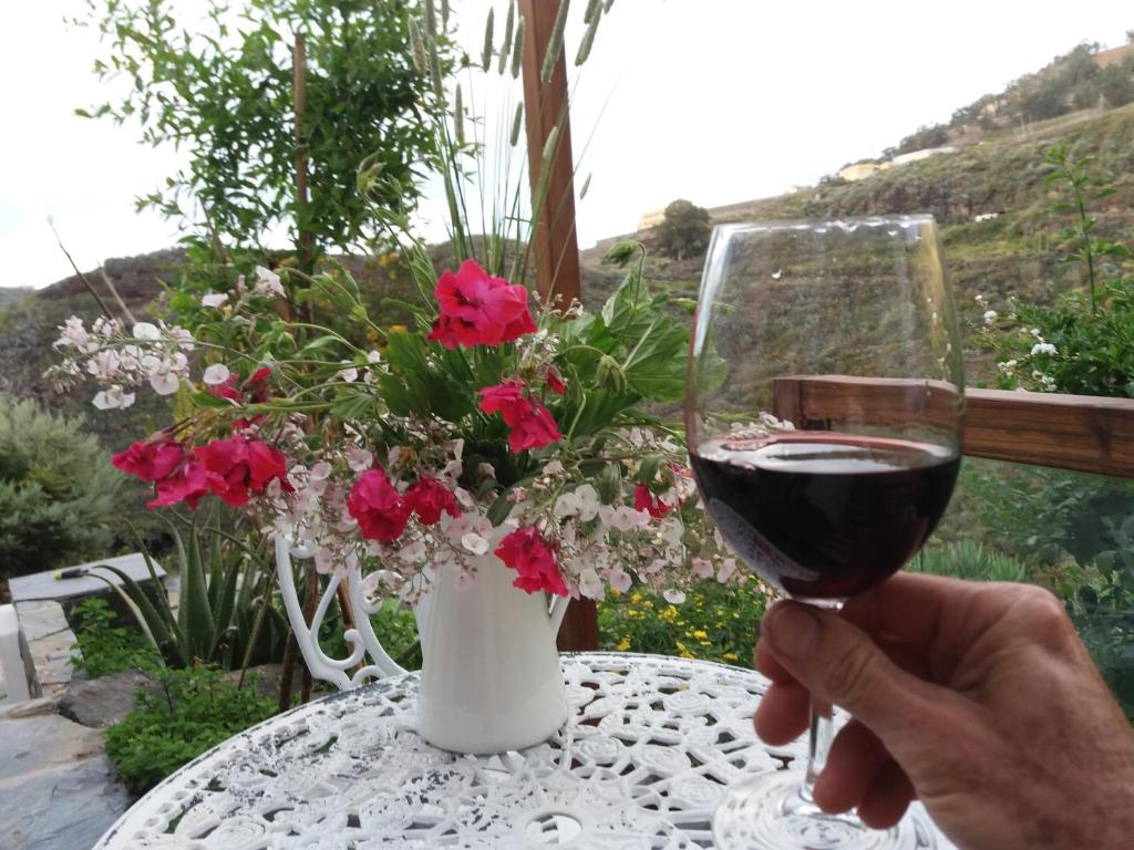FirgasLa cueva de Ángel B&B的把一杯葡萄酒放在鲜花桌子上的人