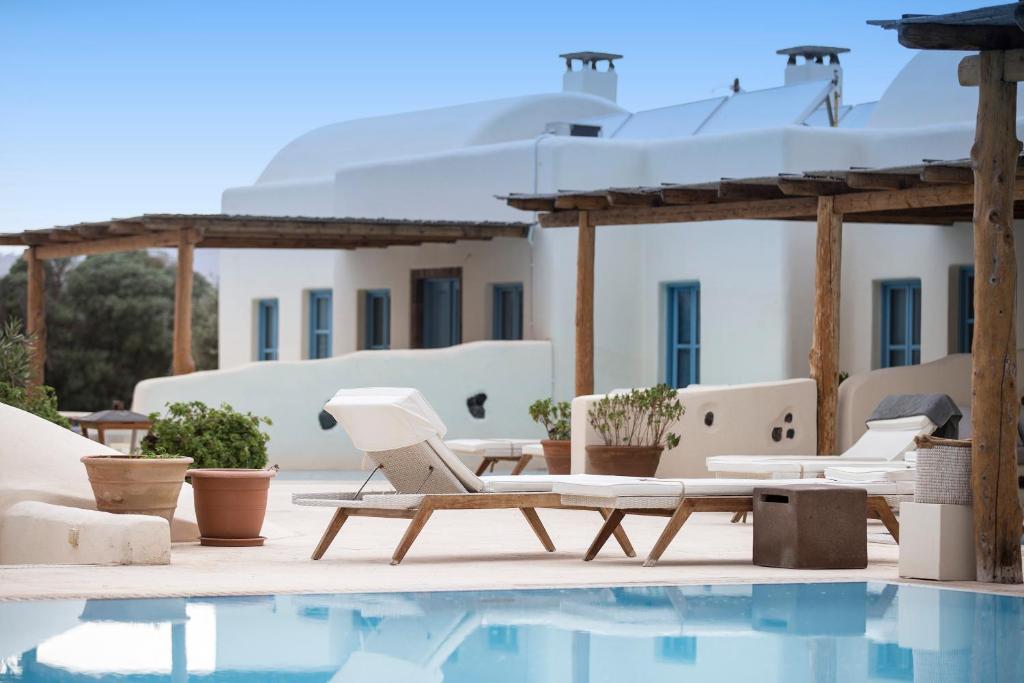 佩里沃罗黑玫瑰海滩套房酒店的房屋旁的游泳池配有桌椅