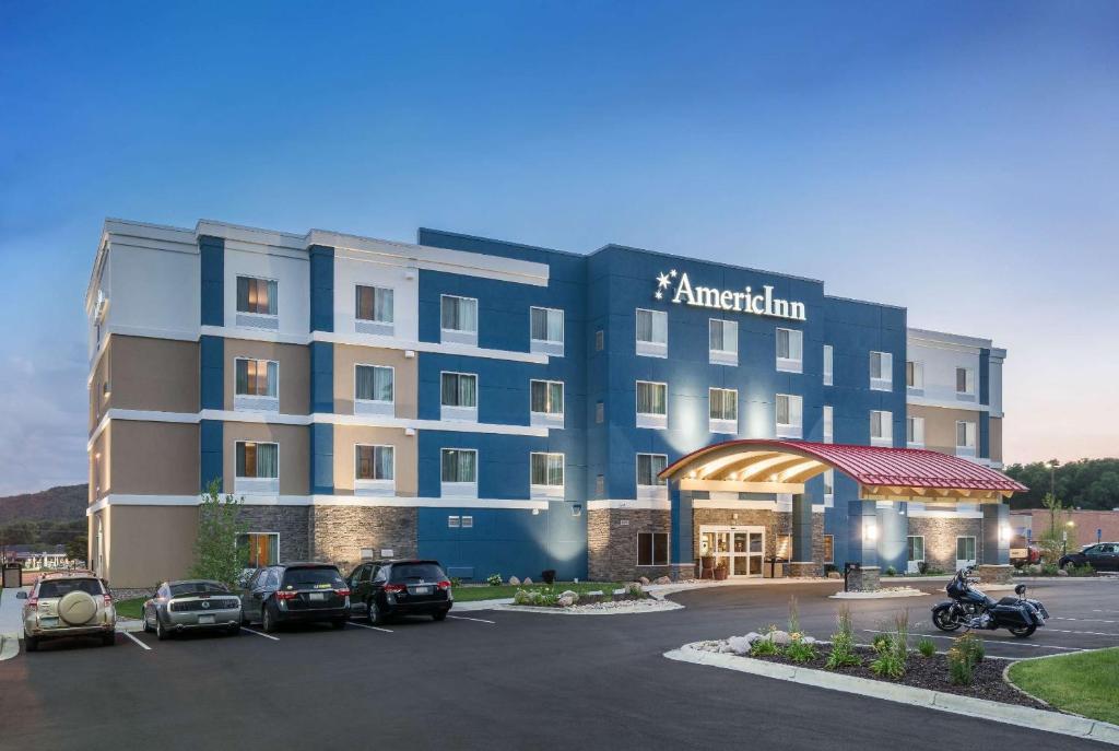 苏福尔斯AmericInn by Wyndham Sioux Falls North的停车场内有车辆的旅馆