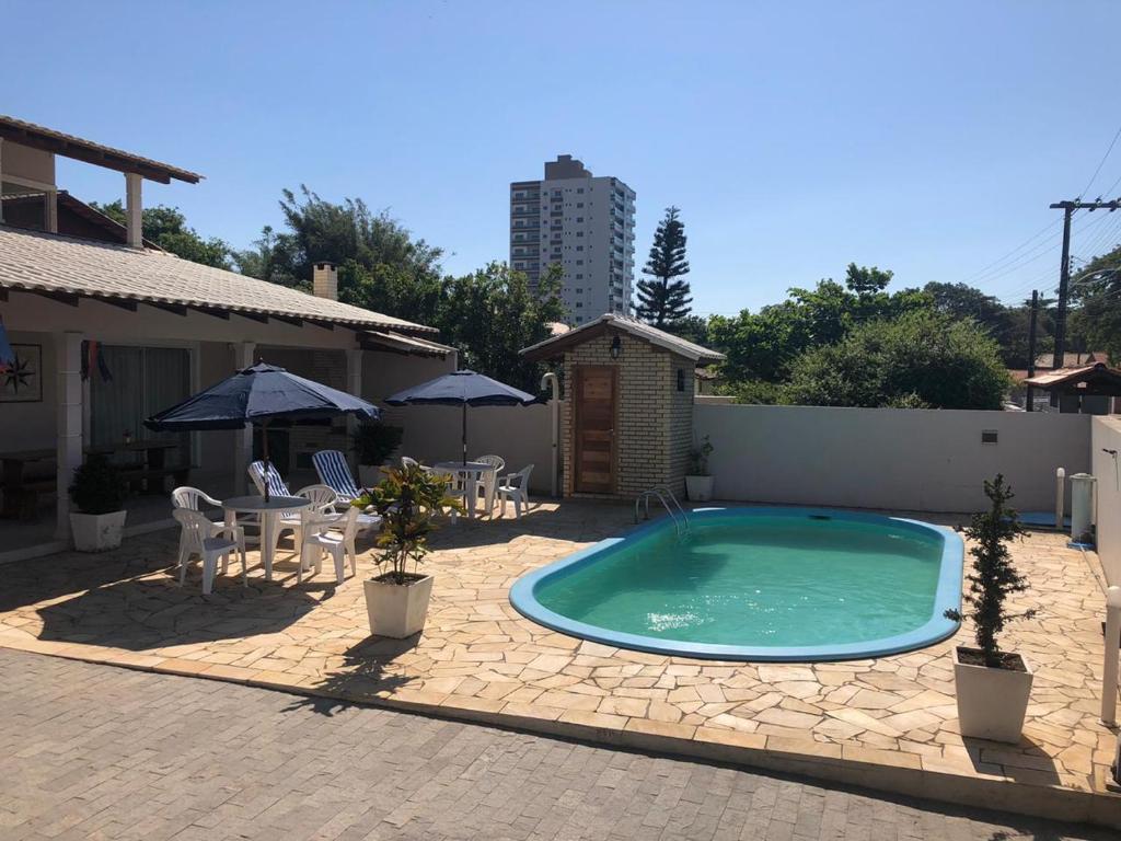 佩尼亚Mundo Livre Guest House的一个带椅子、桌子和遮阳伞的游泳池