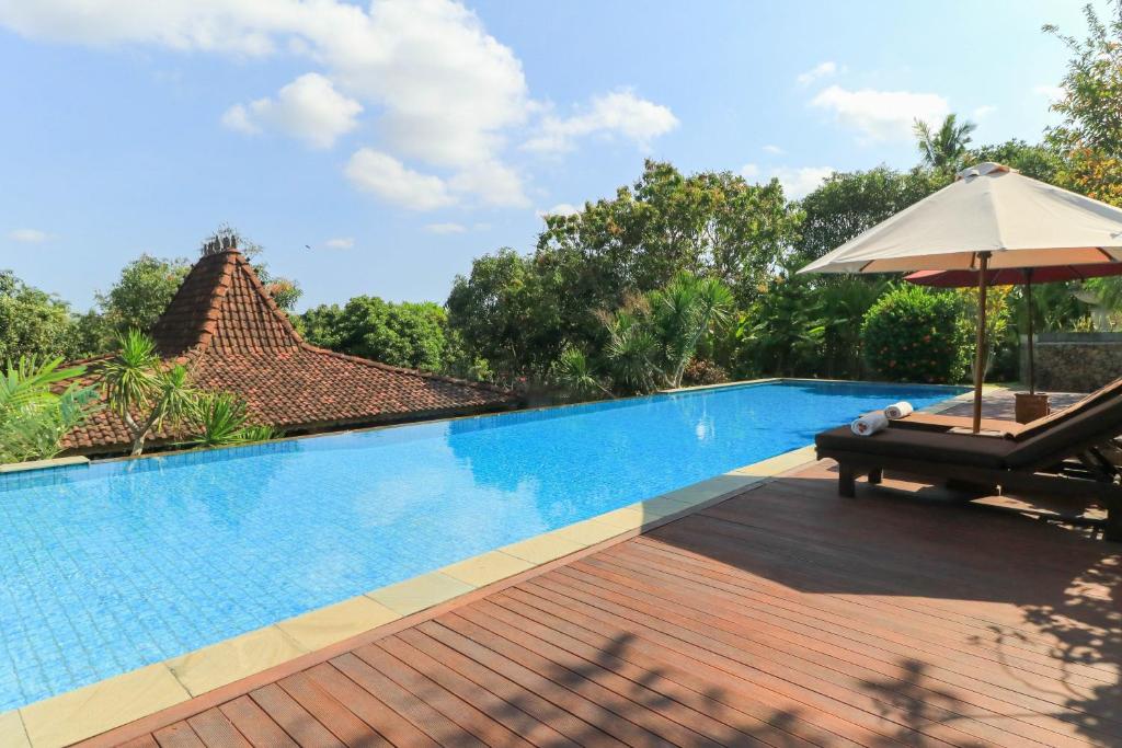 塔巴南沙燕别墅度假酒店的一个带椅子和遮阳伞的游泳池