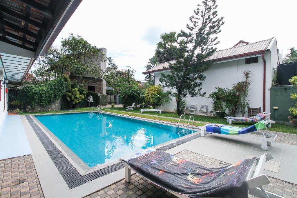 尼甘布Lioni Holidays Villa的庭院内的游泳池,带椅子