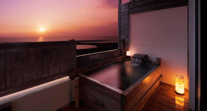 伊豆阿如栖旅馆的阳台上的热水浴池,享有日落美景