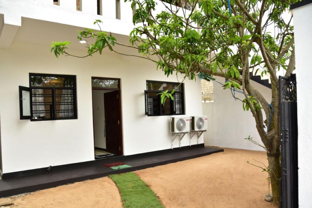 希克杜沃Hikkaduwa Beach House的一间拥有白色墙壁和树的房间