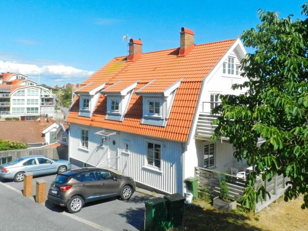 吕瑟希尔5 person holiday home in LYSEKIL的一座带橙色屋顶的房子,前面停有汽车