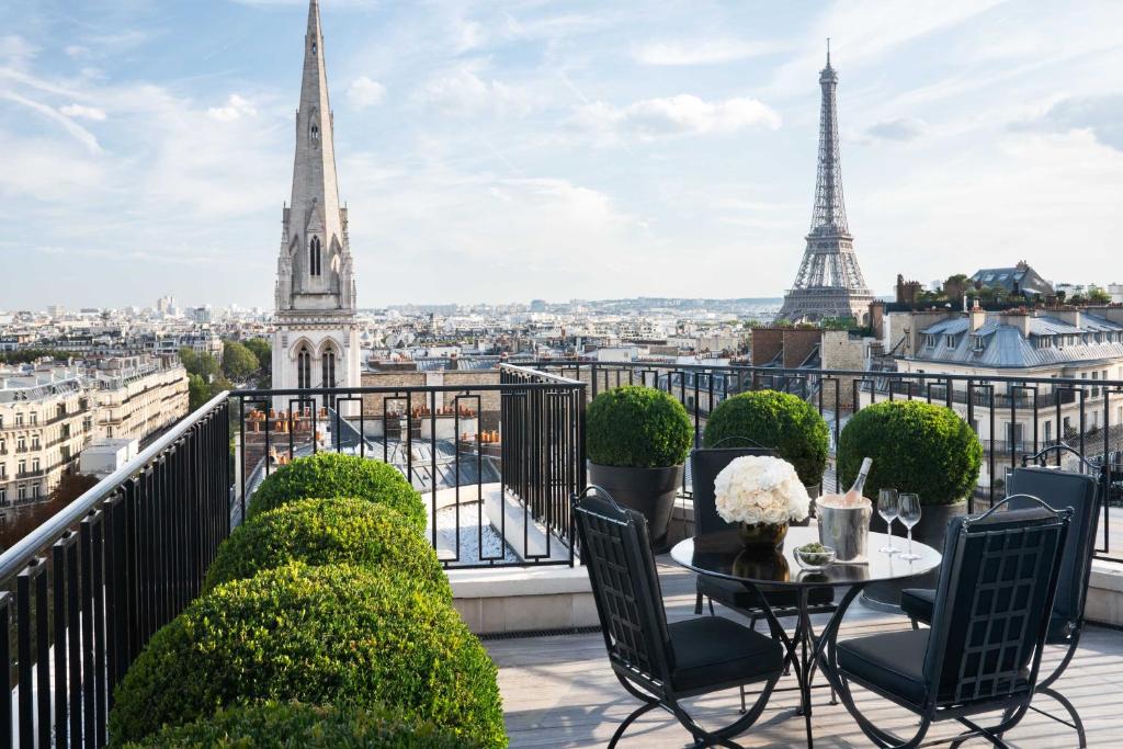 巴黎乔治五世巴黎四季酒店的阳台配有桌椅和艾菲尔铁塔
