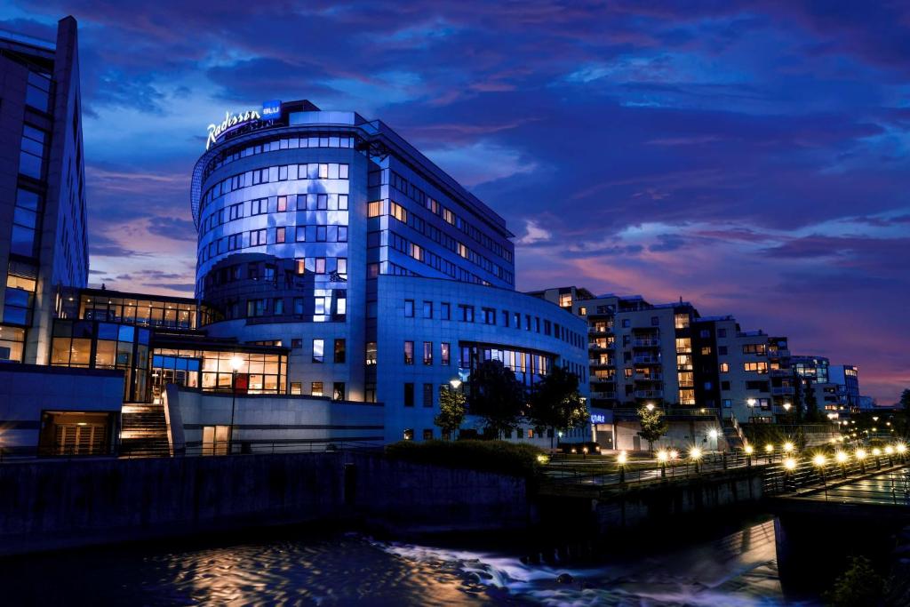 奥斯陆奥斯陆尼达兰丽笙酒店的城市的一座建筑,晚上有灯光