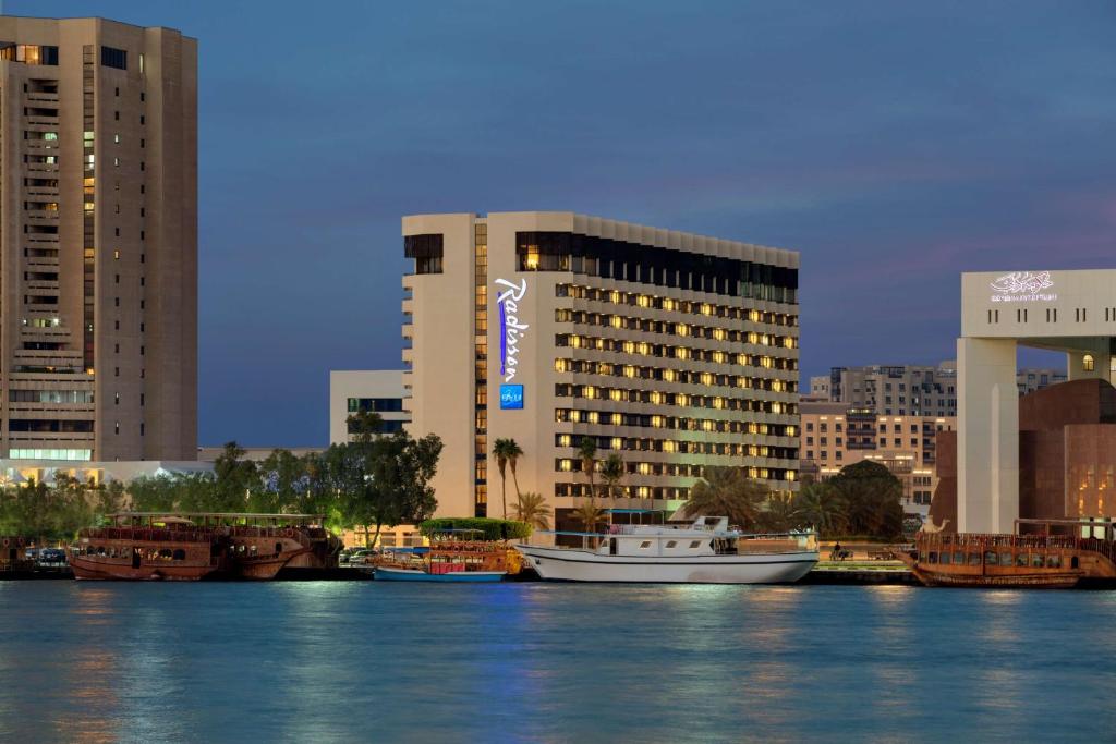 迪拜迪拜德伊勒河丽笙酒店的一群船在水中,在建筑物前