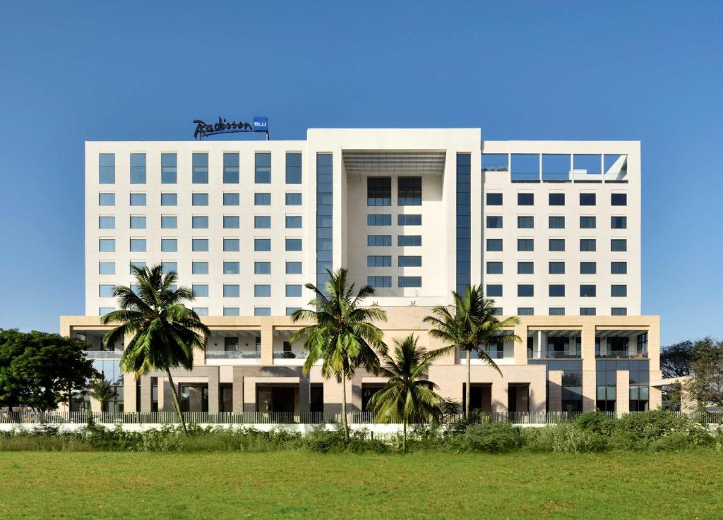 哥印拜陀哥印拜陀丽笙酒店的一座白色的大建筑,前面有棕榈树