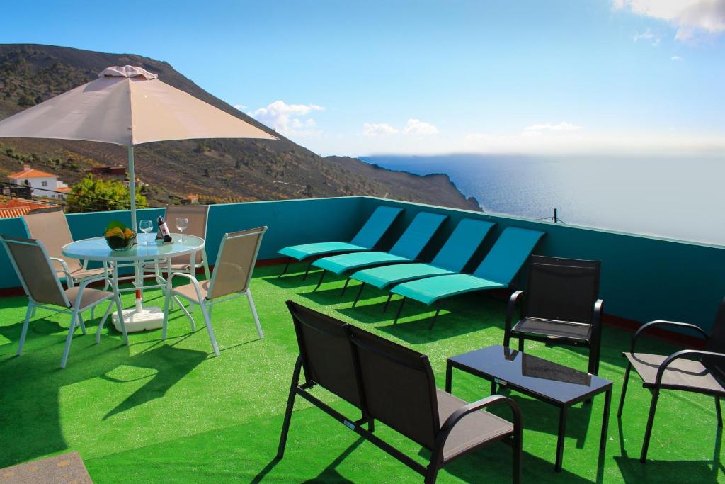 丰卡连特德拉帕尔马Surf House la Palma的庭院配有桌椅和遮阳伞。