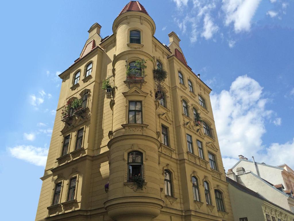 维也纳第七天堂维也纳中心公寓的一座黄色高楼,上面有盆栽植物