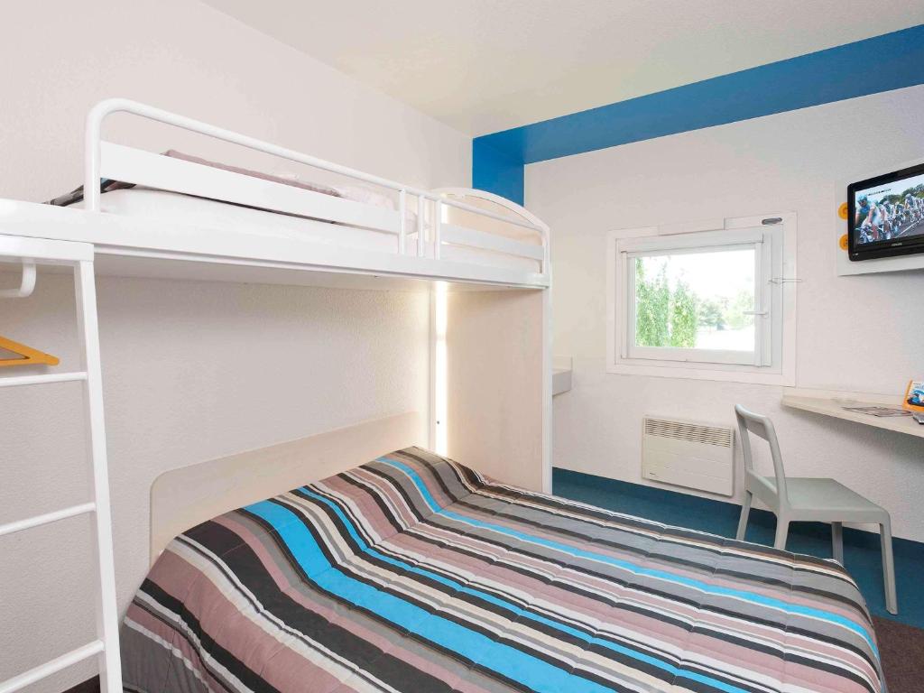 图尔图尔北F1酒店的一间小卧室,配有双层床和书桌