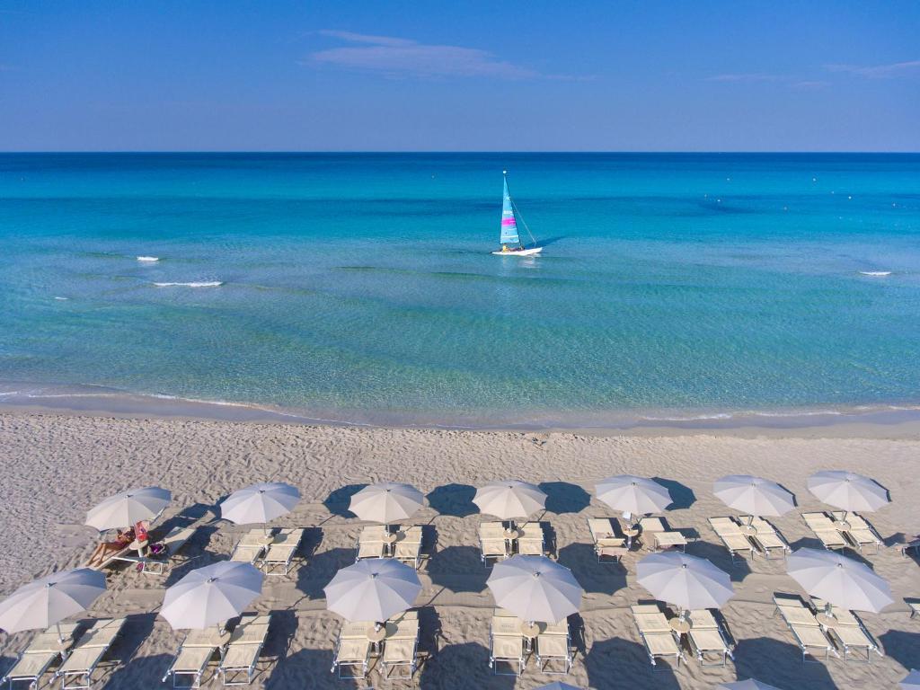 乌真托Vivosa Apulia Resort的海滩上的一群遮阳伞和一艘船