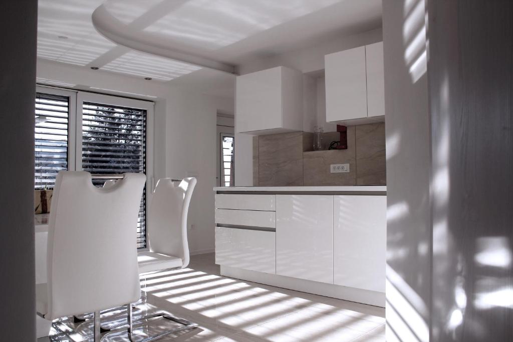 勒什Deluxe Apartments Panorama的白色的厨房配有白色橱柜和白色椅子