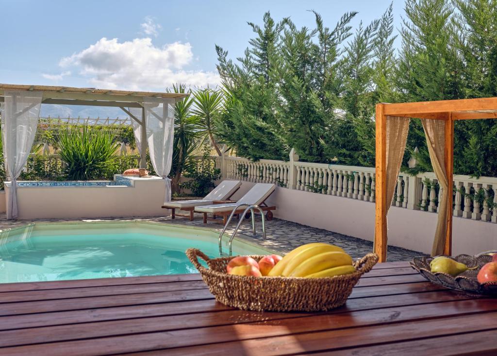 拉加纳斯Three Graces Holiday Houses Complex的坐在游泳池旁甲板上的一篮水果