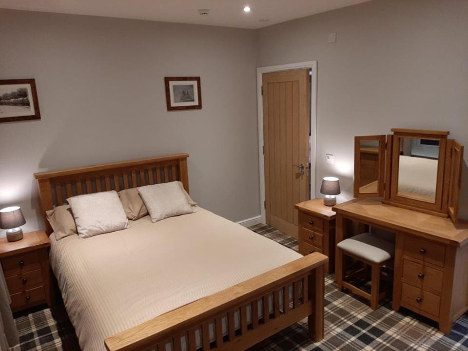贝灵汉姆Fountain Cottage, Bellingham, Northumberland的一间卧室配有一张床、一张书桌和一台电视